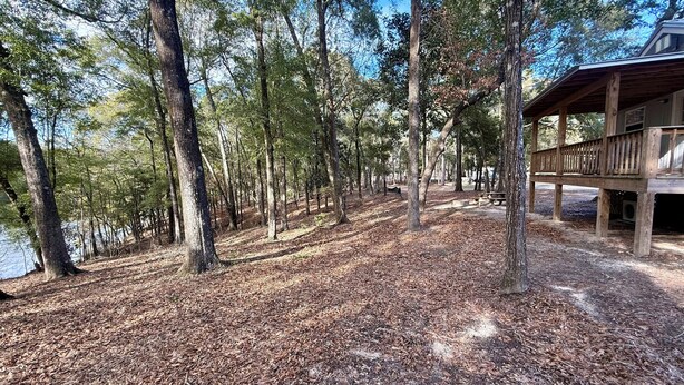 A cabin with a deck overlooking a forested area and a body of water. - Charming Pondview Cabin (Andalusia)