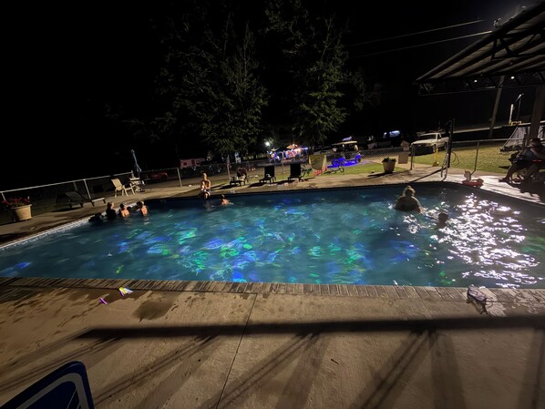 A swimming pool at night with people around it.