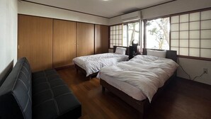 A bedroom with two beds, a wooden wardrobe, a bench, and a window with a view of trees. - HatagoyaChuube (Hakui)