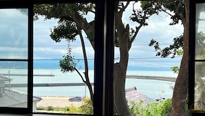 A room with a view of a body of water and a bridge. There are trees in front of the window. - HatagoyaChuube (Hakui)