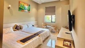 A hotel room with a bed, a desk, a chair, a television, and a painting on the wall.