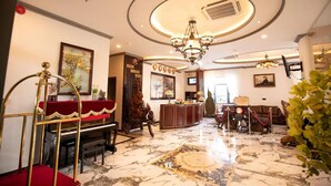 A lobby with a grand piano, a reception desk, and a chandelier.