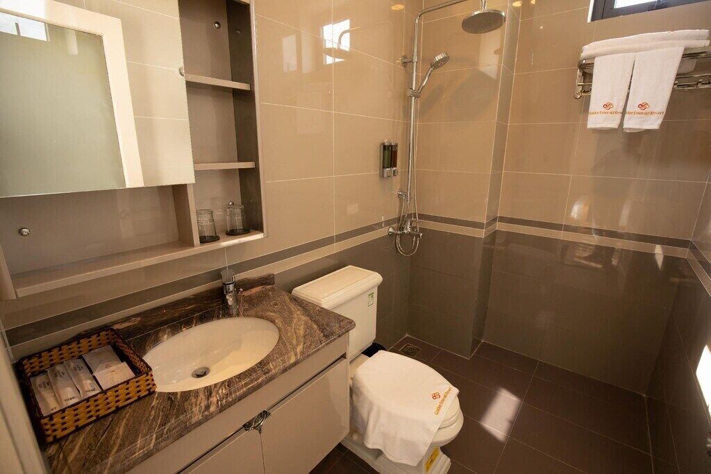 Un baño moderno con lavamanos de mármol, inodoro y ducha con cerramiento de vidrio.