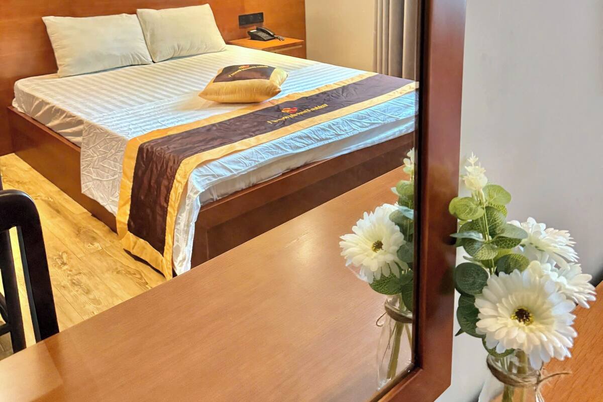 Une chambre d’hôtel avec un lit, une table de chevet, une lampe et un tableau accroché au mur.