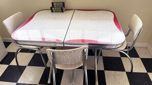 A dining table with a checkered floor, four chairs, and a wall-mounted light fixture.