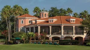 A large, two-story building with a red-tiled roof, multiple balconies, and a central tower. -  Family friendly 2-bedroom Full kitchen. Golf ,pools.restaurants,activities. (Orlando)