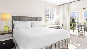 A hotel room with a large bed, a desk with a chair, a window with blinds, and a balcony with outdoor furniture. -  Family friendly 2-bedroom Full kitchen. Golf ,pools.restaurants,activities. (Orlando)