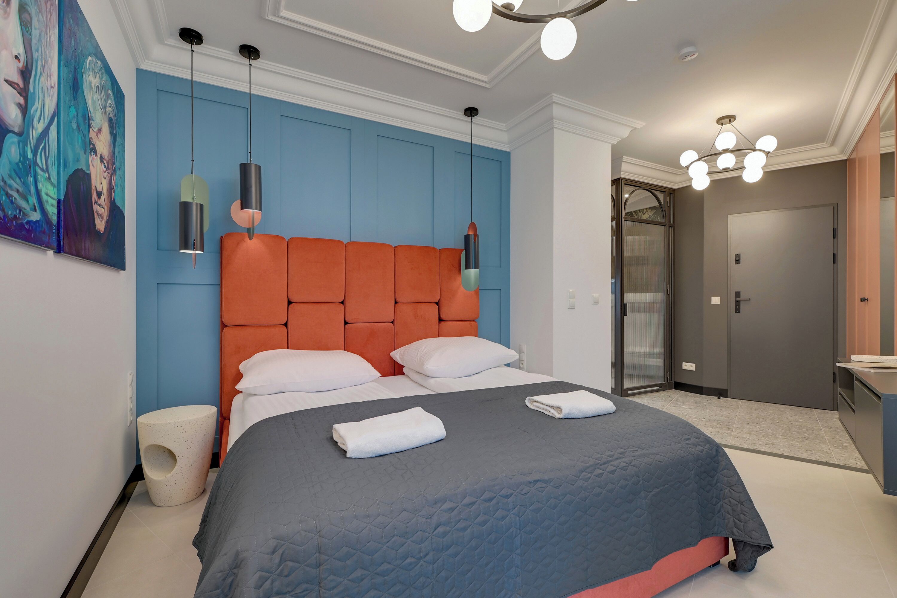 Ein modernes Hotelzimmer mit einem großen Bett, einem orangefarbenen Kopfteil und einem Bild an der Wand.