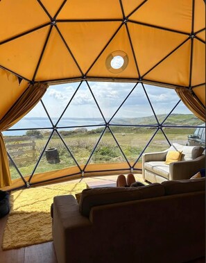 Una tienda en forma de cúpula geométrica con vistas a un paisaje costero.