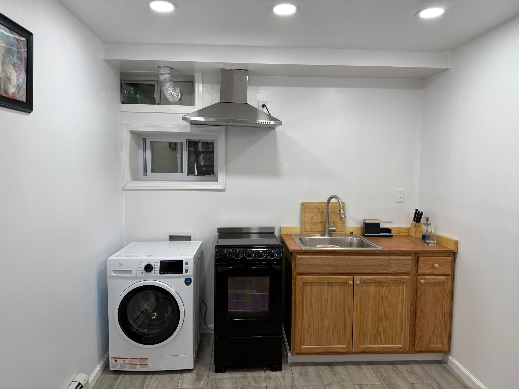 A compact kitchen with a washing machine, an oven, and wooden cabinets.