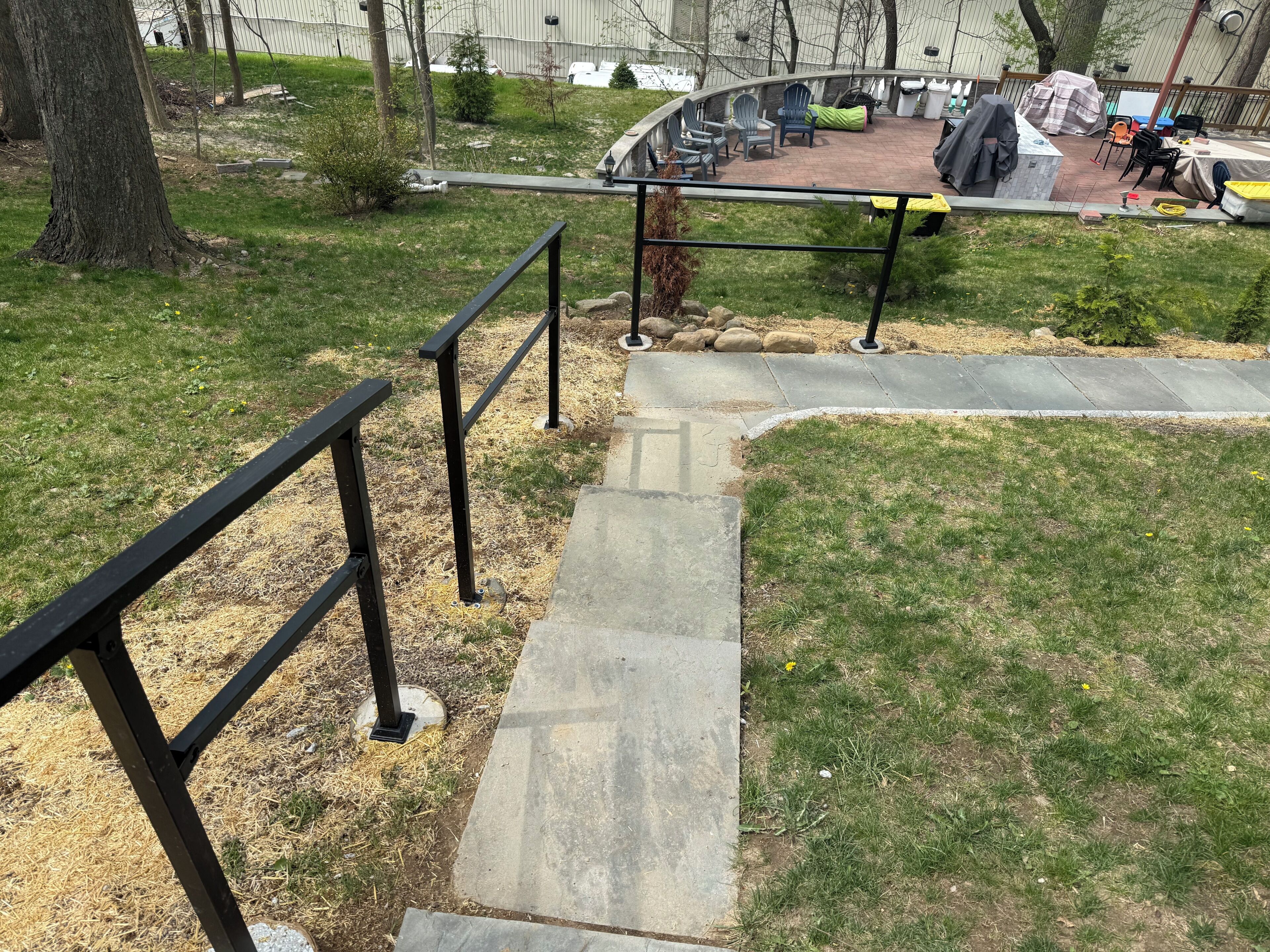 A concrete staircase with metal railings leading to a covered outdoor area with chairs and tables.