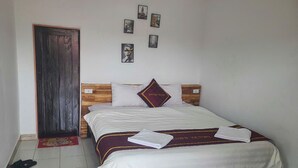 A neatly made bed with a white and maroon bedspread, a pillow with a maroon and gold design, and a pair of towels on the bed. - VANG VIENG VICTORY HOSTEL  (Vang Vieng)