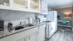 Een moderne keuken met witte kastjes, een granieten aanrecht, een ingebouwde magnetron, een fornuis en een spoelbak.