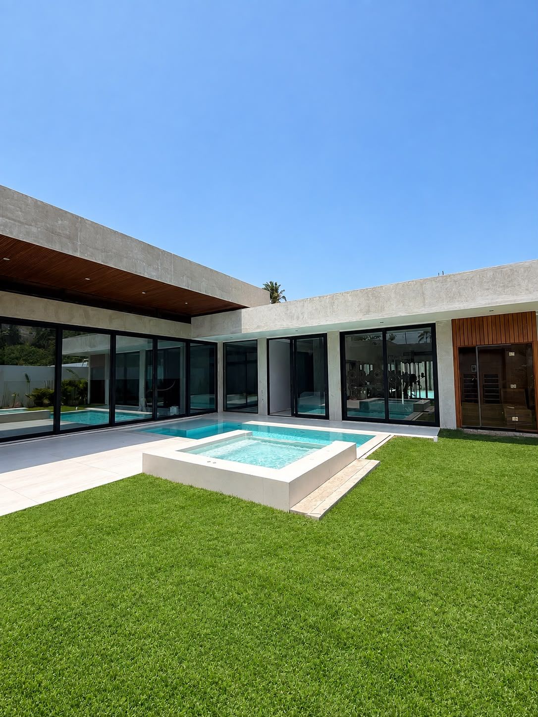 A modern house with a swimming pool, large glass windows, and a well-maintained lawn.