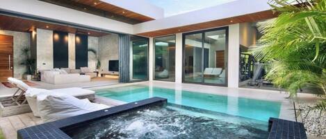 Una casa moderna con piscina, mobiliario exterior y un jacuzzi.