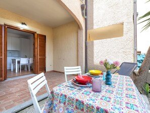 En udendørs terrasse med spisebord, stol og liggestol.