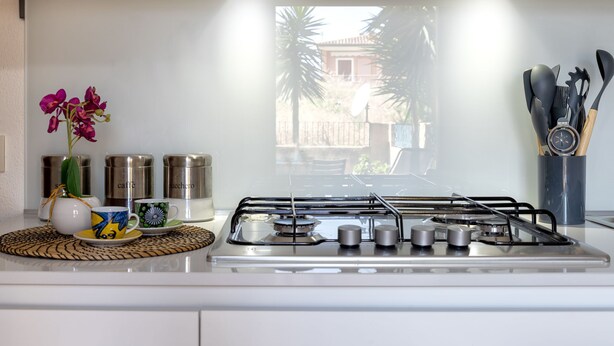 A modern kitchen with a gas stove, stainless steel containers, and a decorative orchid.