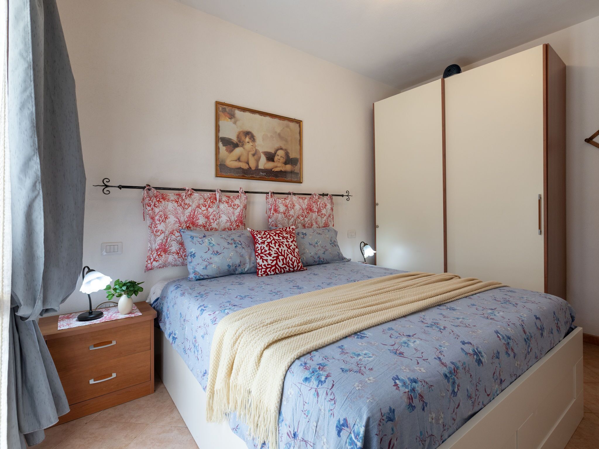 Un dormitorio con una cama, una mesita de noche, una lámpara, un cuadro y un armario.