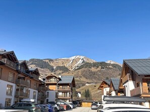 Une station de montagne avec des bâtiments en bois, des balcons et un espace de stationnement.