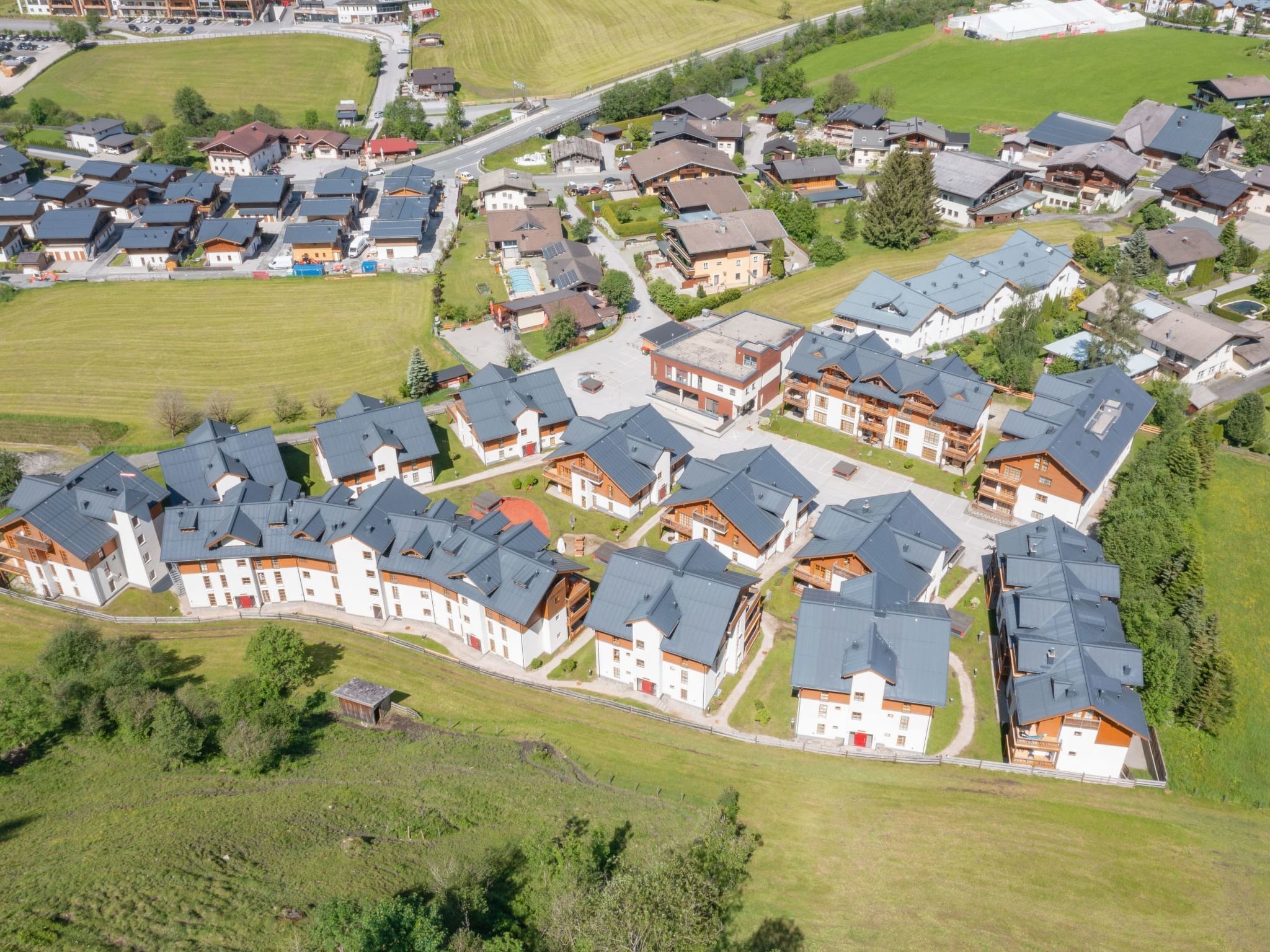 An aerial view of a residential area with multiple houses, roads, and green spaces.
