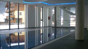 A spacious indoor area with a reflective floor, large windows, and a staircase.