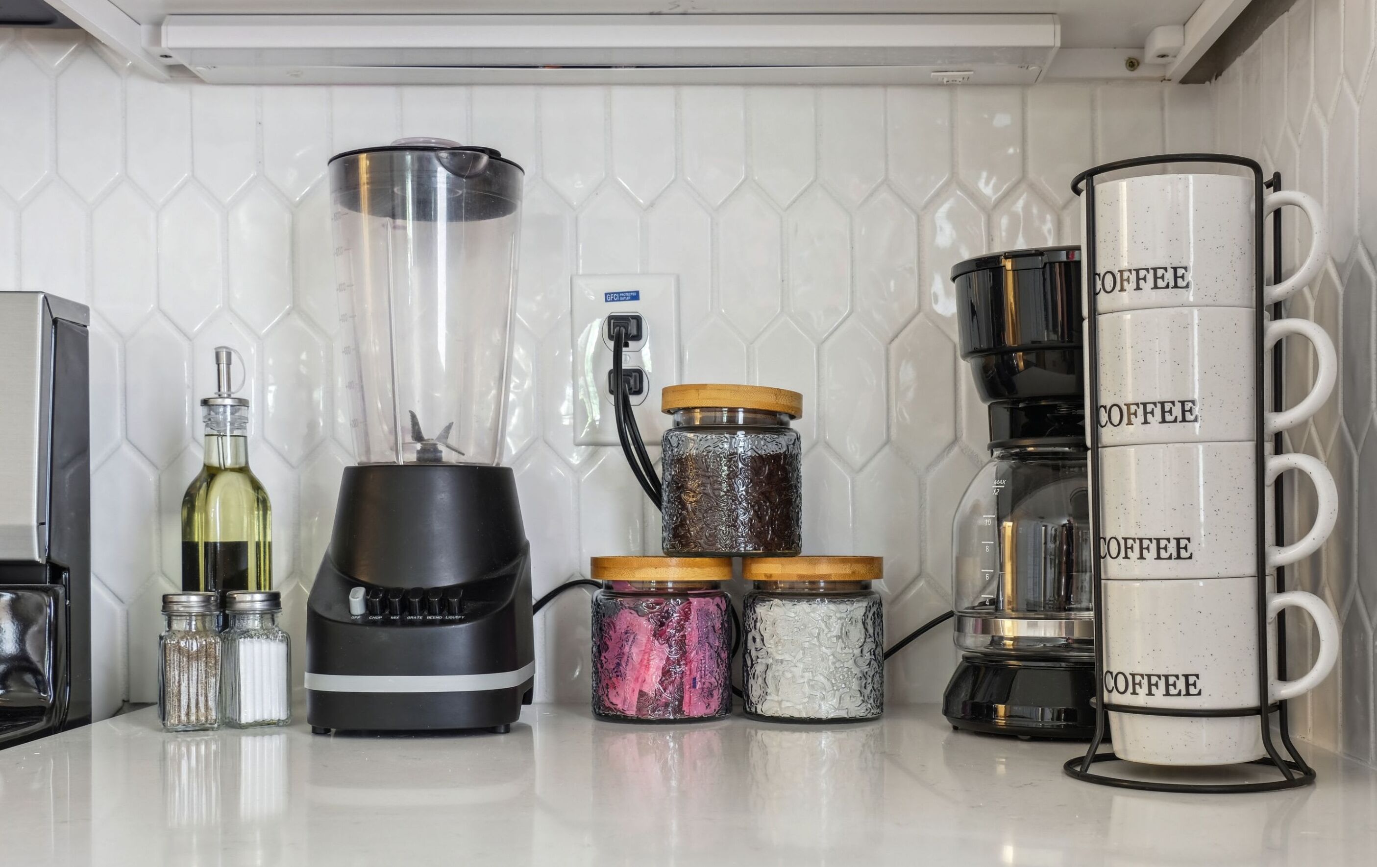 Eine Küchenarbeitsplatte mit Kaffeemaschine, Mixer und zwei Gewürzbehältern.