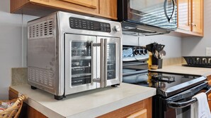 Une cuisine équipée d’un four en acier inoxydable, de meubles de rangement en bois, d’un four à micro-ondes et d’une cuisinière.