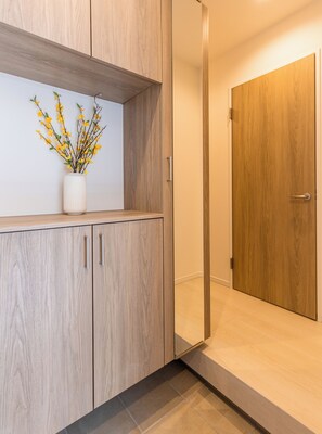 Un interior moderno con armarios de madera, un jarrón blanco con flores amarillas y una puerta de madera.