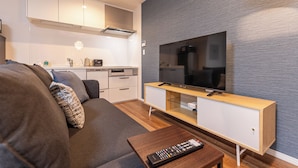 Ein modernes Wohnzimmer mit einer Couch, einem Holztisch und einem Fernseher auf einem Holzschrank.
