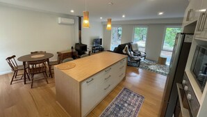 Una cocina moderna con una isla central, sillas de madera, una mesa de comedor y una estufa empotrada.
