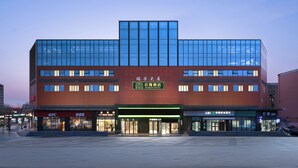 Een modern hotel met een glazen gevel, meerdere verdiepingen en een opvallende entree.