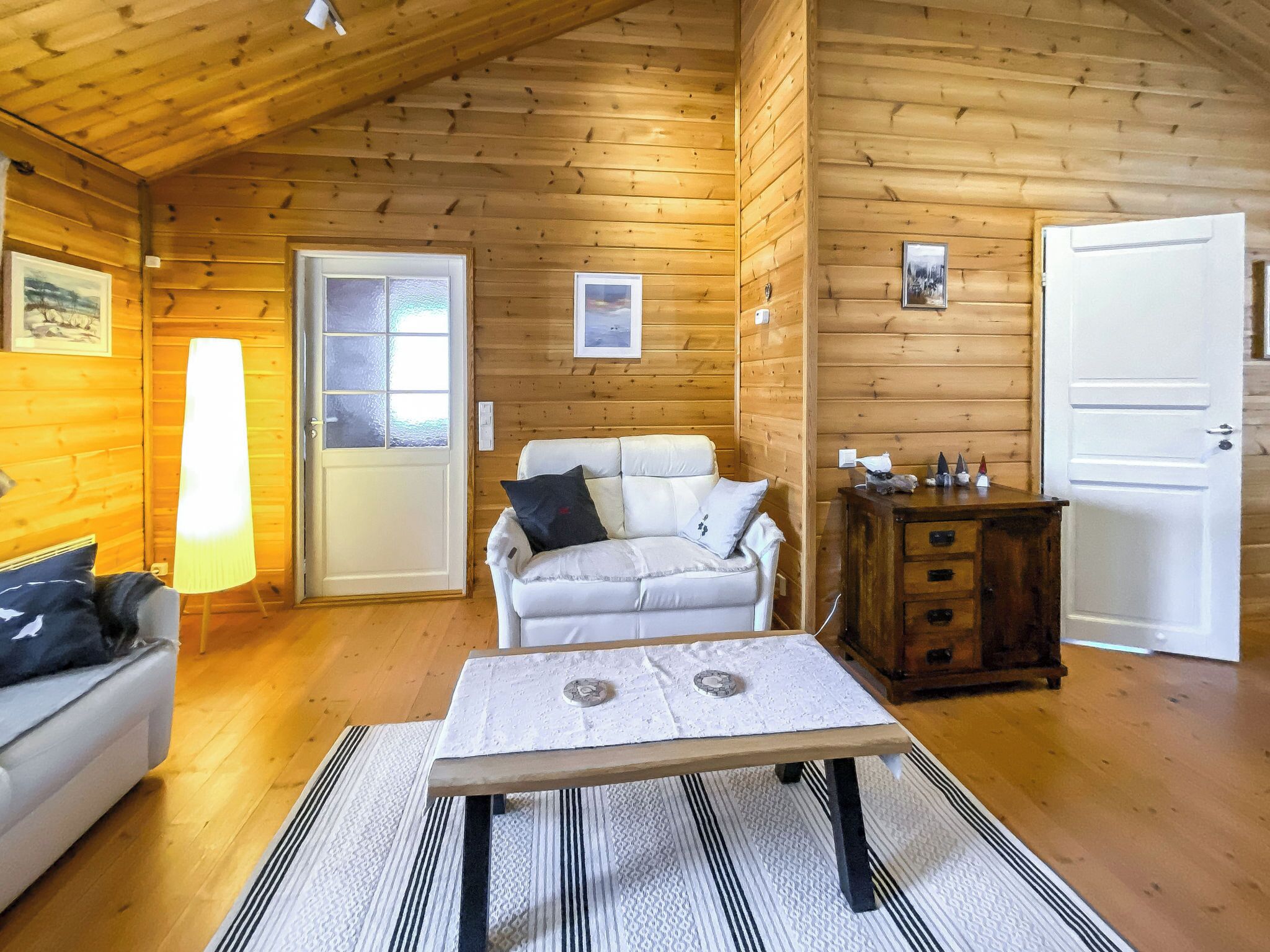 Interior de una cabaña de madera con un sofá, una mesa y un armario.