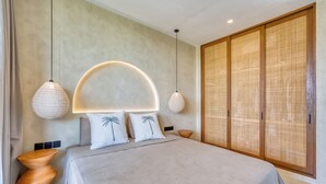 A modern bedroom with a large bed, two bedside lamps, a wooden wardrobe, and a wall-mounted light fixture.