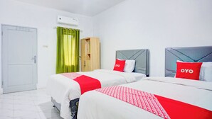 Habitación de hotel con dos camas, un armario y un equipo de aire acondicionado.