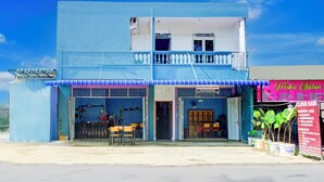 Un edificio de dos pisos con fachada azul, un balcón en el piso superior y un escaparate con el letrero "Friska Salon".