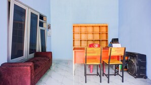 Una habitación con un sofá rojo, un escritorio de madera con dos sillas y un calentador negro.