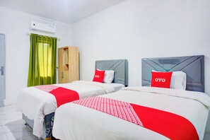 A hotel room with two beds, each with a grey headboard and red pillows. There is a wooden wardrobe and a green curtain. - Hotel O Clove Nari Homestay (Medan)