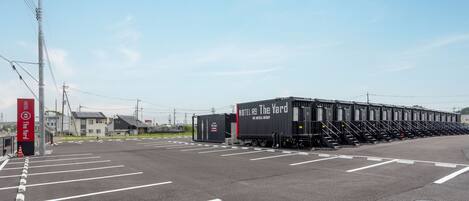 A parking lot with a row of hotel containers labeled "HOTEL 9 The Yard" and a hotel sign.