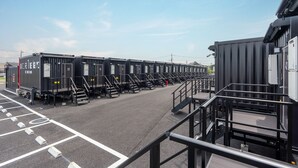 Un'area di parcheggio con file di container neri, ognuno contrassegnato da un numero.
