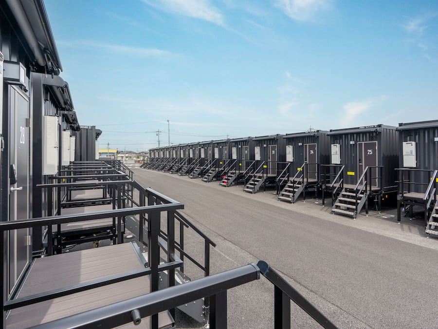 A row of uniform, industrial-style portable cabins with external stairs and railings, likely used for temporary accommodation.