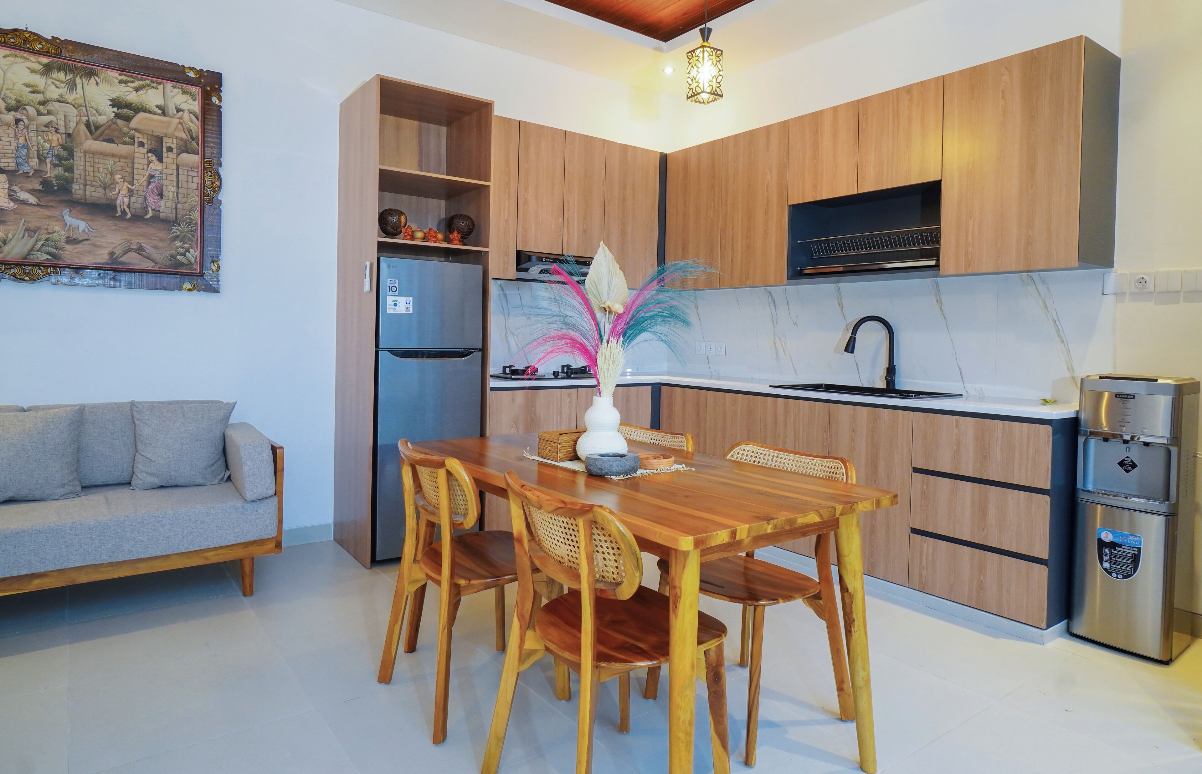 Una cucina moderna con mobili in legno, un tavolo da pranzo con sedie, un frigorifero, un lavello e un vaso decorativo.