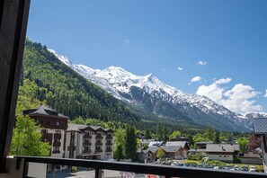 Un pueblo de montaña con picos nevados, edificios tradicionales y un cielo despejado.