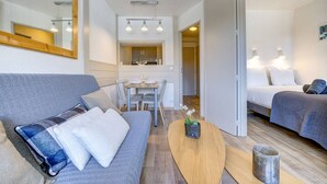 Ein kompaktes Hotelzimmer mit Schlafsofa, Esstisch, Bett und Küchenzeile.