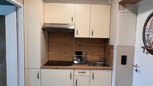 Una cocina compacta con armarios blancos, encimera de madera y horno integrado.