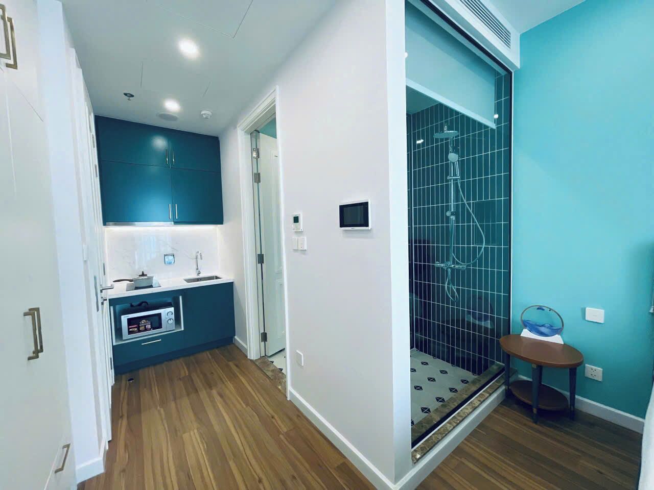 A modern bathroom with a shower, a small table, and a microwave.