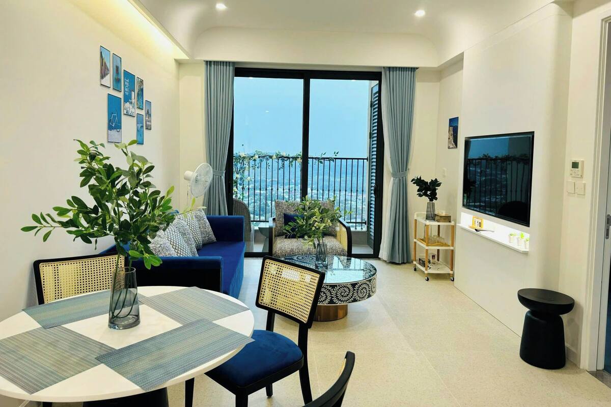 A modern living room with a balcony, a dining area, and a TV.