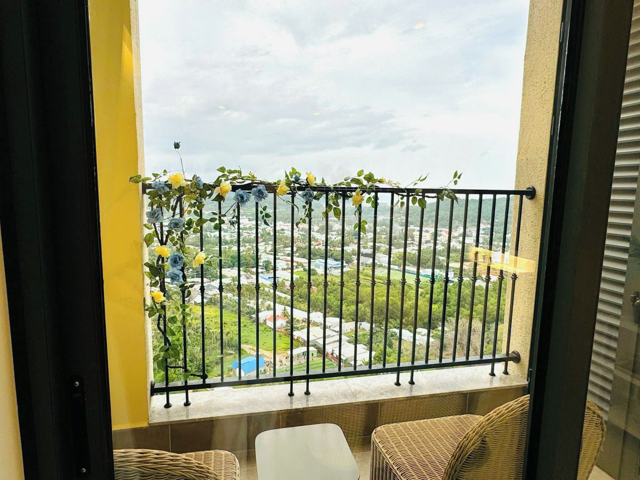 A balcony with a metal railing, wicker furniture, and a view of a cityscape.