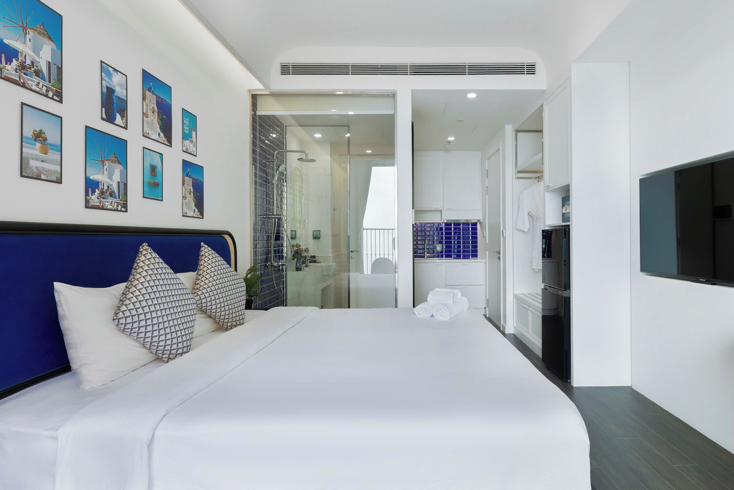 A modern hotel room with a large bed, a TV, and a bathroom visible through an open door.