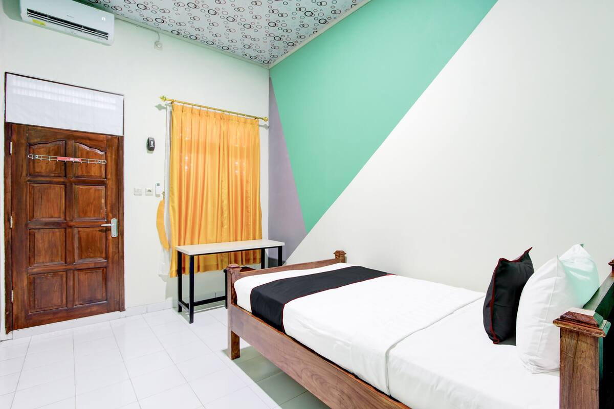 Un dormitorio con una cama de madera, un colchón blanco y una pared verde.
