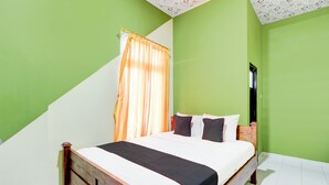 Une chambre à coucher avec un lit, des murs verts, une fenêtre avec des rideaux et une porte.